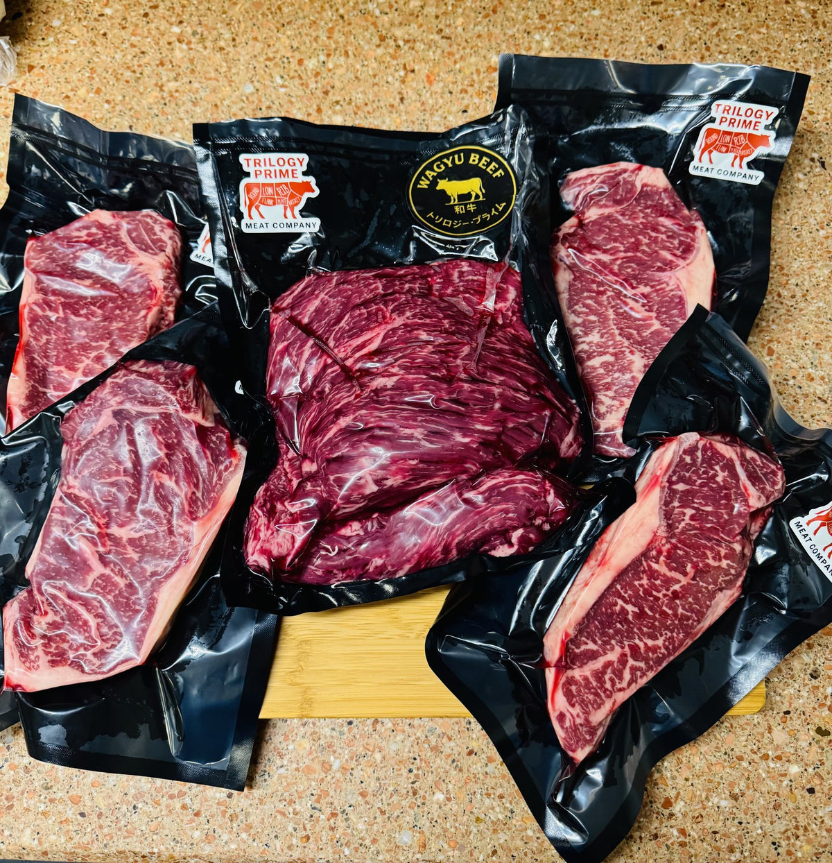 Trilogy Prime Wagyu steaks in branded vacuum packs on a granite counter